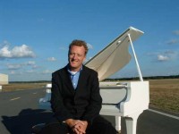 Howard Goodall at a white grand piano